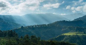 Photograph of sunlight poking through clouds onto mountains