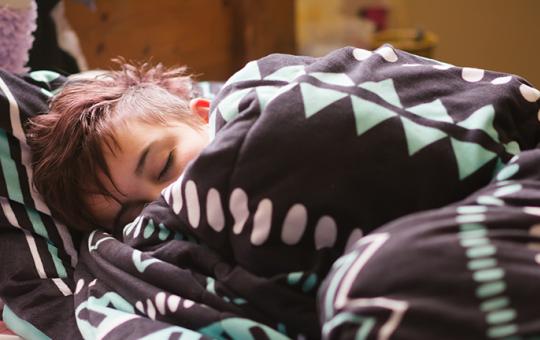 Teenager asleep and wrapped in a blanket