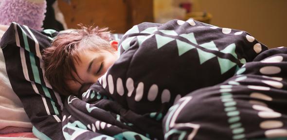 Teenager asleep and wrapped in a blanket