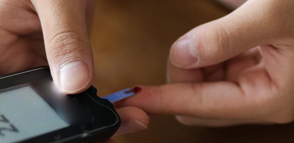 An Asian teenager with type 1 diabetes uses an at home glucometer to test his blood sugar levels