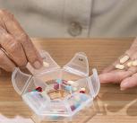 Elderly woman putting pills into pill box for the week - stock photo